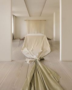 a white bed sitting in the middle of a room next to a table and chairs