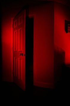 an open door in a dark room with red light coming from the top and bottom