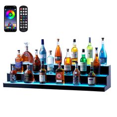 there are many liquor bottles on the shelf with remotes next to it and an iphone in the background