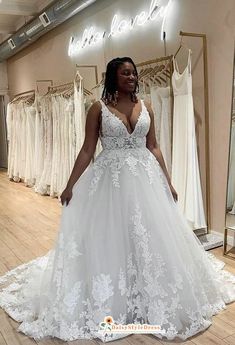 a woman standing in front of a dress on display at a bridal gown shop