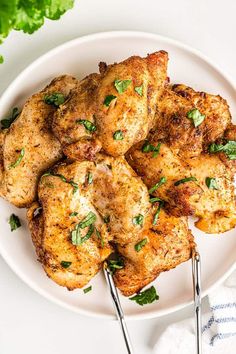 chicken on a white plate with two forks and parsley in the middle, ready to be eaten