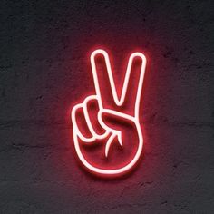 a neon sign with the word peace written on it in front of a brick wall