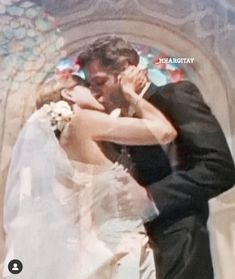 a bride and groom kissing in front of a stained glass window