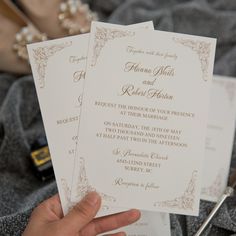 a person holding two wedding cards in their hand