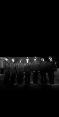 a group of men standing next to each other in front of a truck at night