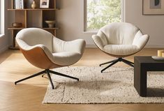 two white chairs sitting on top of a rug in front of a window next to a coffee table