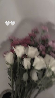 a bunch of white and pink flowers in a vase with hearts on the wall behind it