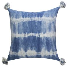 a blue and white tie dyed pillow with tassels on the front, sitting on a