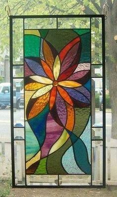 a stained glass window hanging from a chain in front of snow covered houses and trees