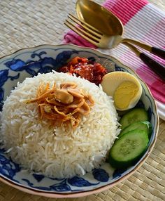 a plate with rice, cucumbers and sauce on it next to a fork