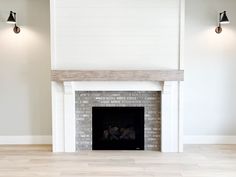 an empty living room with a fireplace and two lamps on either side of the fireplace