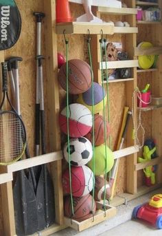 there are many different sports items in the storage area on this shelf, including tennis balls and racquets