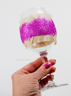 a hand holding a wine glass with pink and gold sprinkles