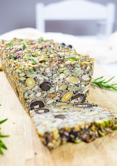 a slice of granola bar sitting on top of a wooden cutting board next to rosemary