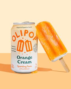 an orange cream popsicle next to a can of orange ice cream on a yellow background