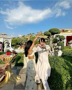 a man and woman walking down a sidewalk next to each other with their arms in the air