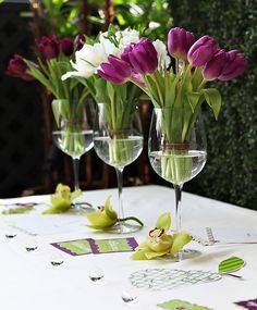 three wine glasses with flowers in them sitting on a table