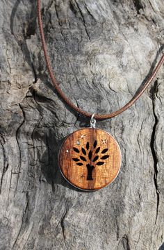 a necklace with a tree on it sitting on top of a piece of drift wood