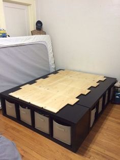 a bed with three storage bins on top of it in the middle of a room