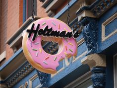 a pink doughnut hanging from the side of a blue building that says hotma's