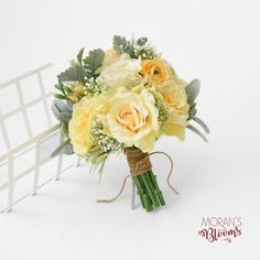 a bridal bouquet with yellow roses and greenery on the stems, tied to a white chair