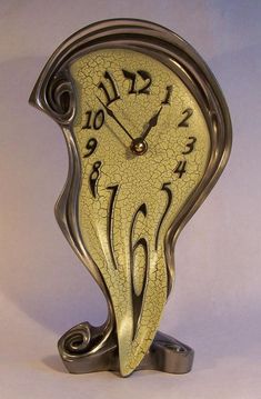 a gold clock with arabic writing on the face and numbers below it, sitting in front of a white background