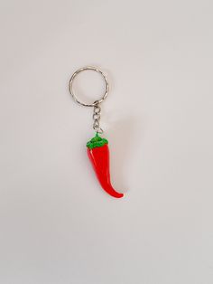 a red pepper shaped keychain hanging from a metal ring on a white surface