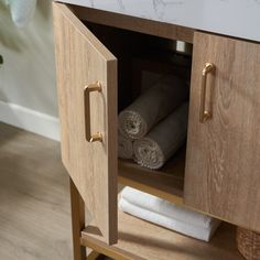 a bathroom cabinet with two towels in it and one rolled up on the counter top