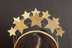 a woman wearing a gold headband with stars on it's side and hair pins in the shape of stars