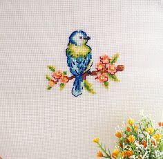 a blue bird sitting on top of a tree branch next to a vase filled with flowers