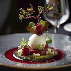 a dessert with raspberries and whipped cream on a plate next to a glass of wine