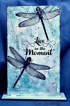 a card with two dragonflies on it and the words live in the moment above them