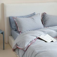 a bed with blue sheets and red piping around the edges, next to a small table