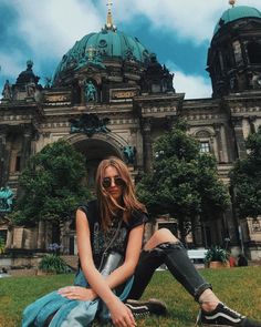 a woman sitting on the ground in front of a large building with a green dome