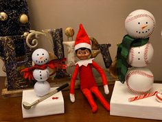 an elf is sitting next to some baseballs and snowmen