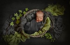 a newborn baby is wrapped in a blanket and laying on it's side with green leaves