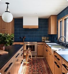 a kitchen with wooden cabinets and blue tile backsplash, an area rug on the floor