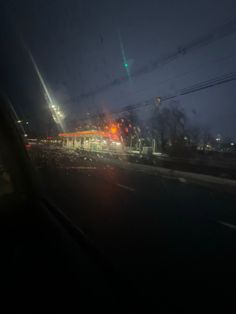 the view from inside a car at night with traffic lights and buildings in the background