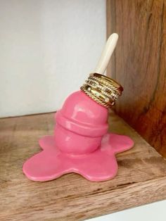 a pink toothbrush holder sitting on top of a wooden shelf