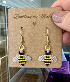 a pair of yellow and black bee earrings sitting on top of a piece of cardboard