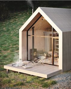 a small wooden cabin with an open door on the outside, sitting in gravel and grass