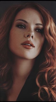 a woman with long red hair is looking at the camera