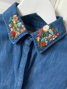 a blue jean shirt with embroidered flowers on the collar