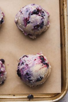 four blueberry donuts sitting on top of a cookie sheet