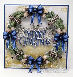 a christmas card with a wreath and bells on the front, decorated in blue ribbon