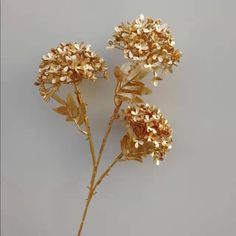 three gold colored flowers on a gray background