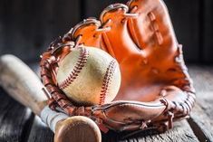 an old baseball glove with a bat and ball in it sitting on a wooden table