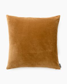 an orange velvet pillow on a white background