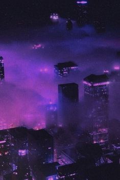 an aerial view of the city at night with purple lights in the sky and fog