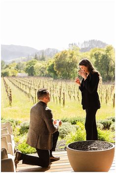 two people sitting on a deck in front of a vineyard